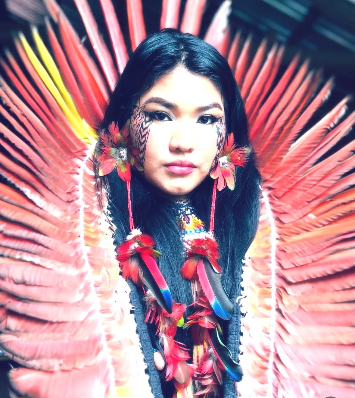 Yaka Yawanawa, nièce de Xinu, en costume cérémoniel avec coiffe de plumes rouges rayonnantes
